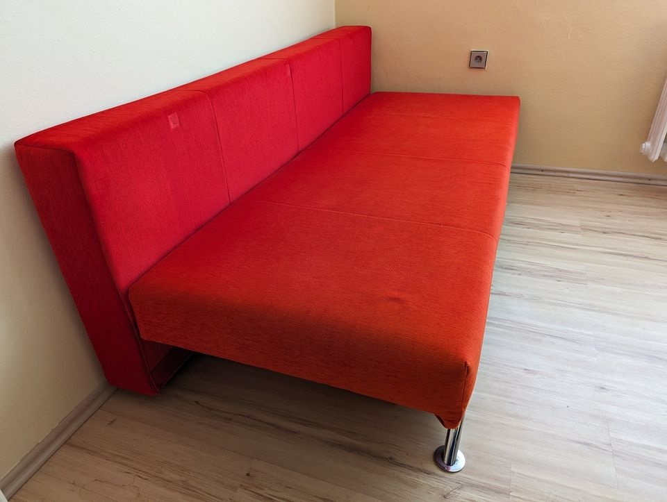 Červený rozkládací gauč s úložným prostorem