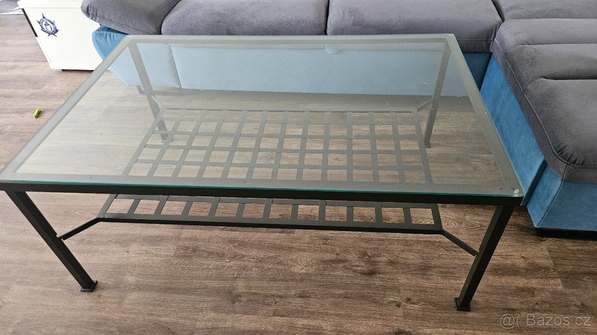 Kovový stůl se skleněnou deskou.