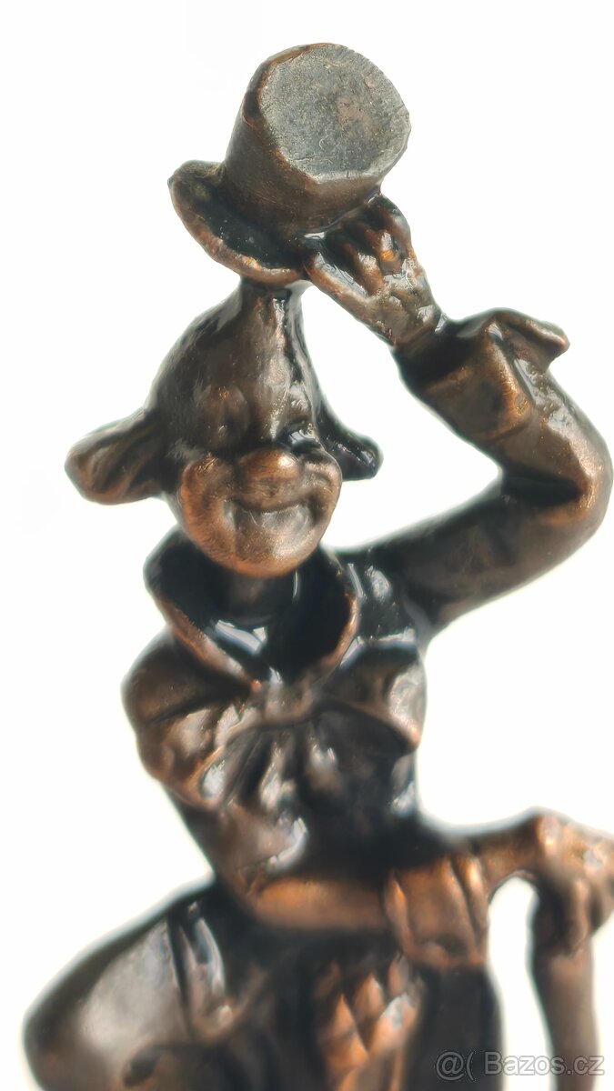 vintage kovová soška klauna na kamenném podstavci