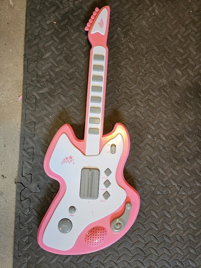 Dětská kytara na baterky v růžovo bílé barvě.