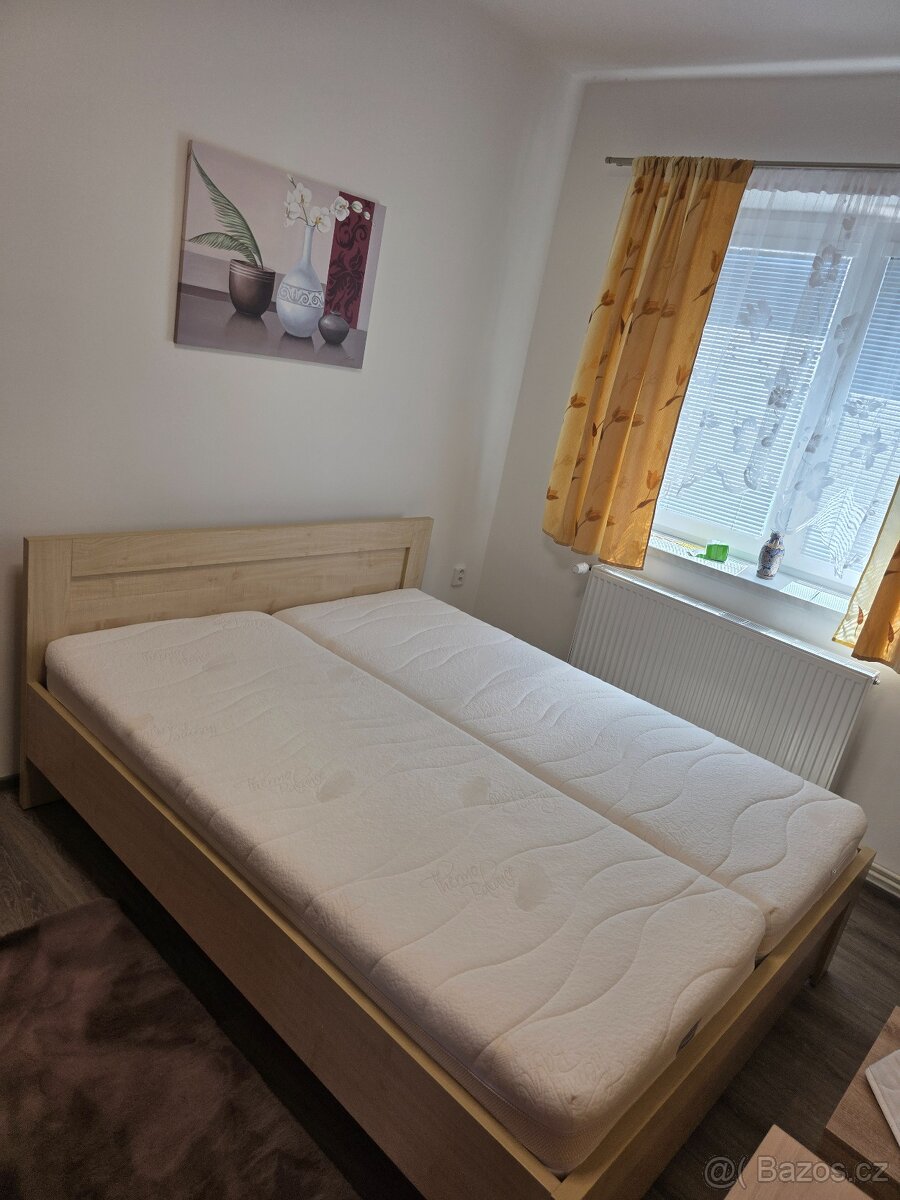 Dřevěná manželská postel.