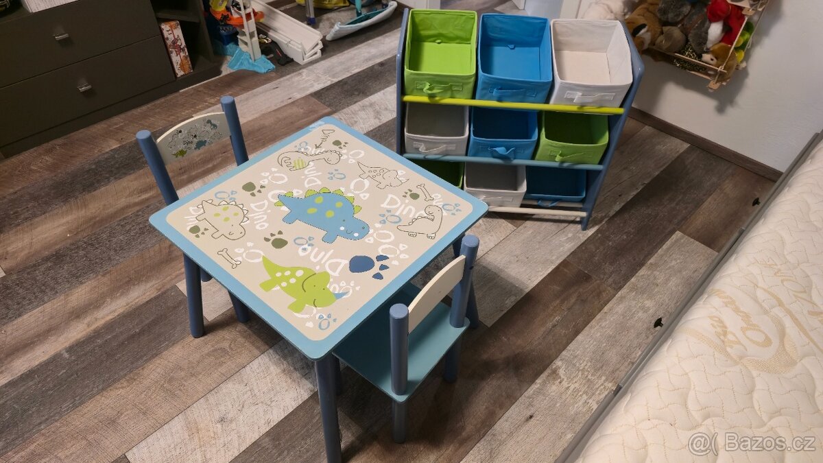 Dětský stolek s židličkami a úložná skříňka s dinosaury.