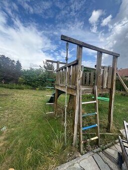 Dětská dřevěná prolézačka se skluzavkou, lanem a houpačkou.