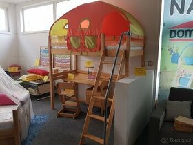 Dětská postel s domečkem a textiliemi.