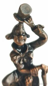 vintage kovová soška klauna na kamenném podstavci