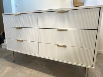 Bílá moderní komoda se zlatými detaily