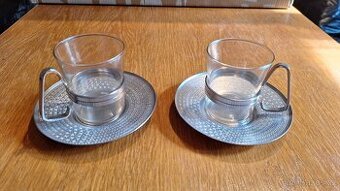 Skleněné šálky s kovovými oušky a kovovými podtácky
