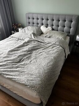Šedá čalouněná postel