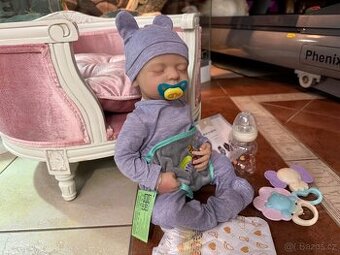 Realistické miminko v šedém overálku N.O.V.É.