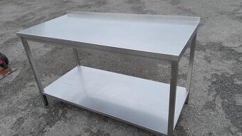 Nerez stůl 150x70x85-90 cm se spodní polici a lemem.