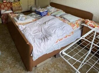 Manželská dvoulůžková postel včetně matrací a peřiny.