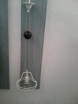 Závěsná funkční kovová lampa bílé barvy nad stůl,