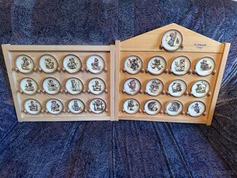 Kompletní sada 25 porcelánových talířků M.I. Hummel v dřevěn