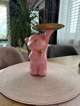 Růžový medvídek z pryskyřice s mašlí a tácem.