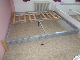 manželská postel s kovovým rámem a dřevěnými nožičky