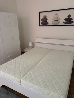 Krásná bílá postel s nočními stolky