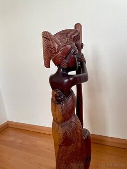 Dřevěná socha ženy s dítětem na zádech