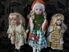 Tři panenky s porcelánovou hlavou na stojánku.