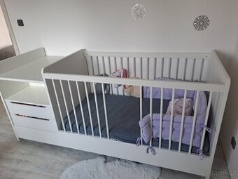 Bílá postýlka s příčkami a matrací a s přebalovacím pultem