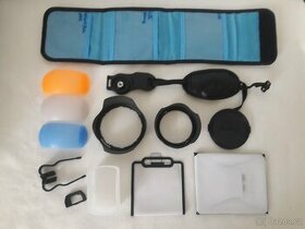 Krytka objektivu, popruh, clona, difuzer, očnice..