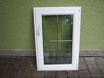 bílé plastové okno se zlatou mřížkou uvnitř