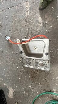 Nerezový dřez s baterii a plynovými hořáky.