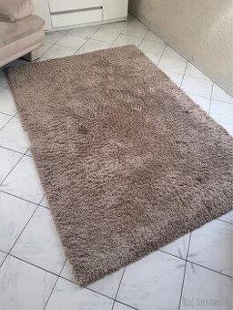 Béžový velký chlupatý koberec.
