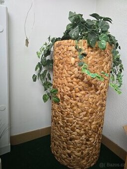 Stojan na květiny ve tvaru válce z pleteného proutí.