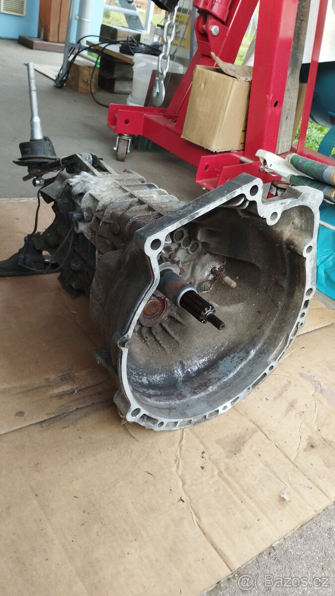 Převodovka BMW E30 s táhly a držákem. - 2