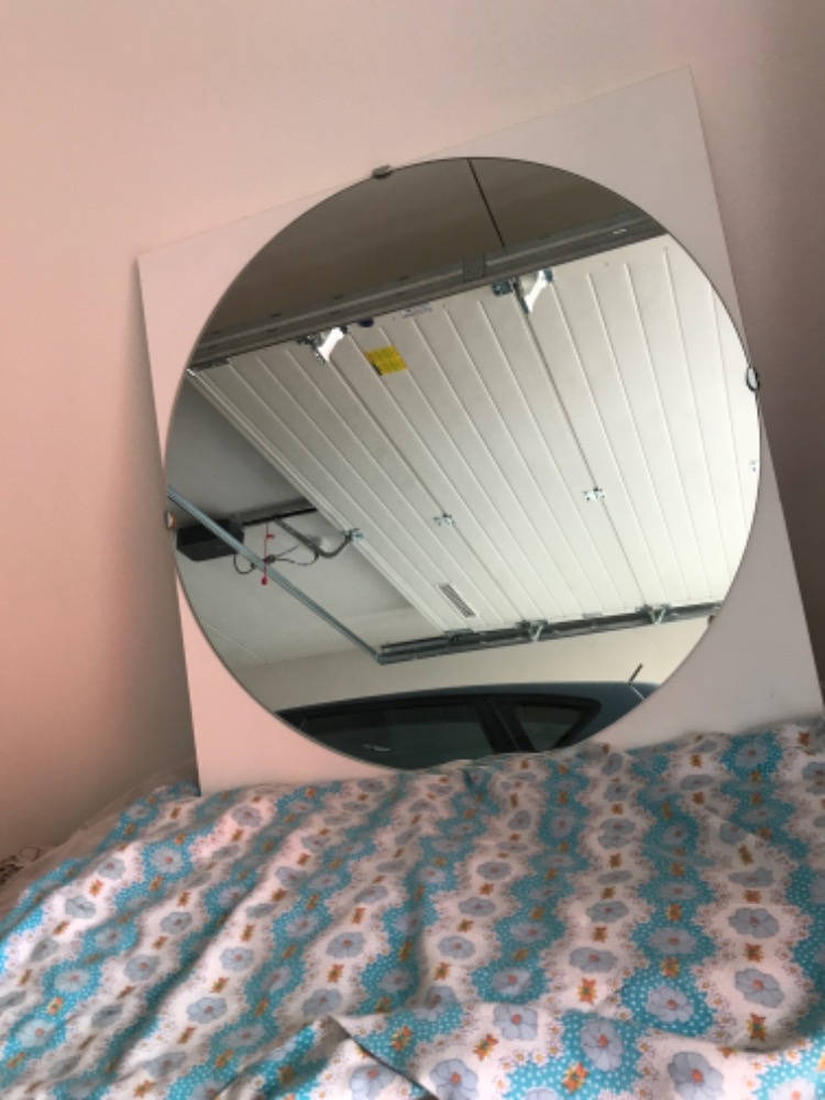 Kulaté zrcadlo na bílé dřevěné desce. - 2